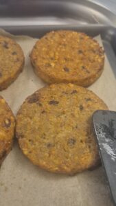 Galettes de céréales crues alignées sur une plaque de cuisson avant le passage au four