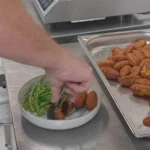 Bol de keftas végétales, haricots verts et sauce blanche en cours de dressage, bac de keftas dorées et saladier de sauce sur le plan de travail