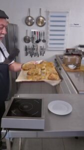 Brik au seitan coupée en deux à la fourchette sur une assiette blanche, le fondant de la compotée visible sous la feuille croustillante.