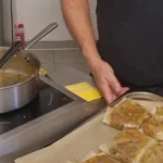 Plaque de briks dorées sur papier cuisson, tenue devant le passe de la cuisine.