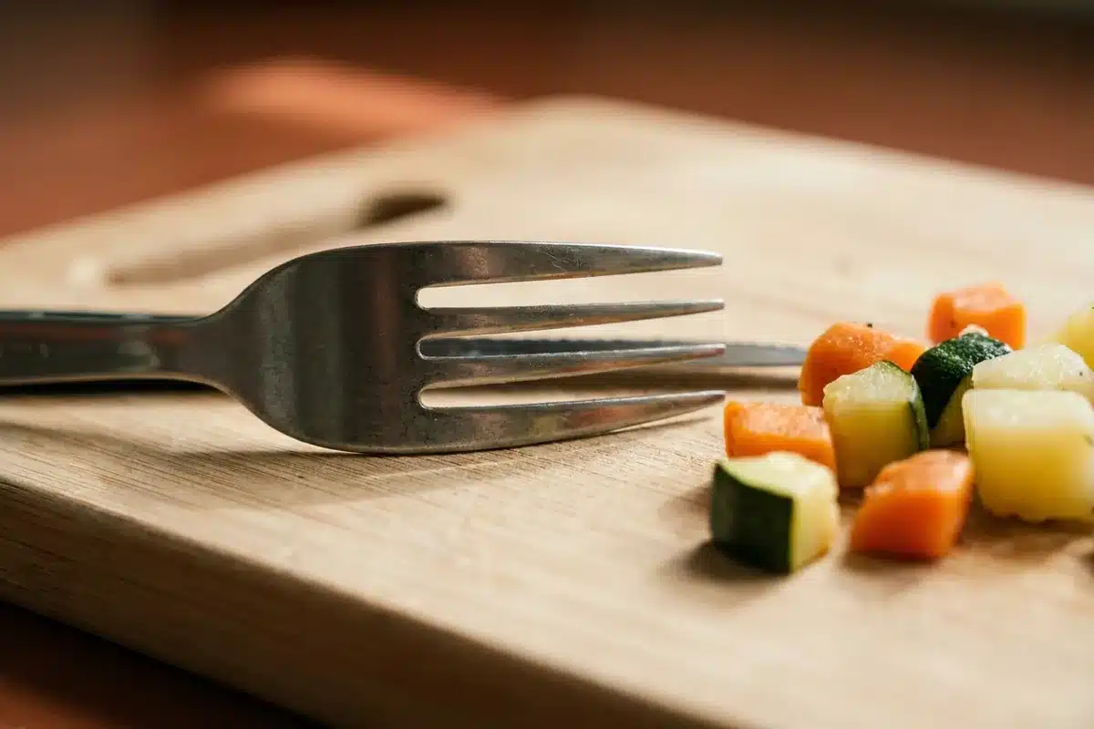 Fourchette métallique standard posée près de morceaux de légumes calibrés