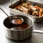 Fond brun de veau limpide couleur acajou, os de veau et légumes rôtis